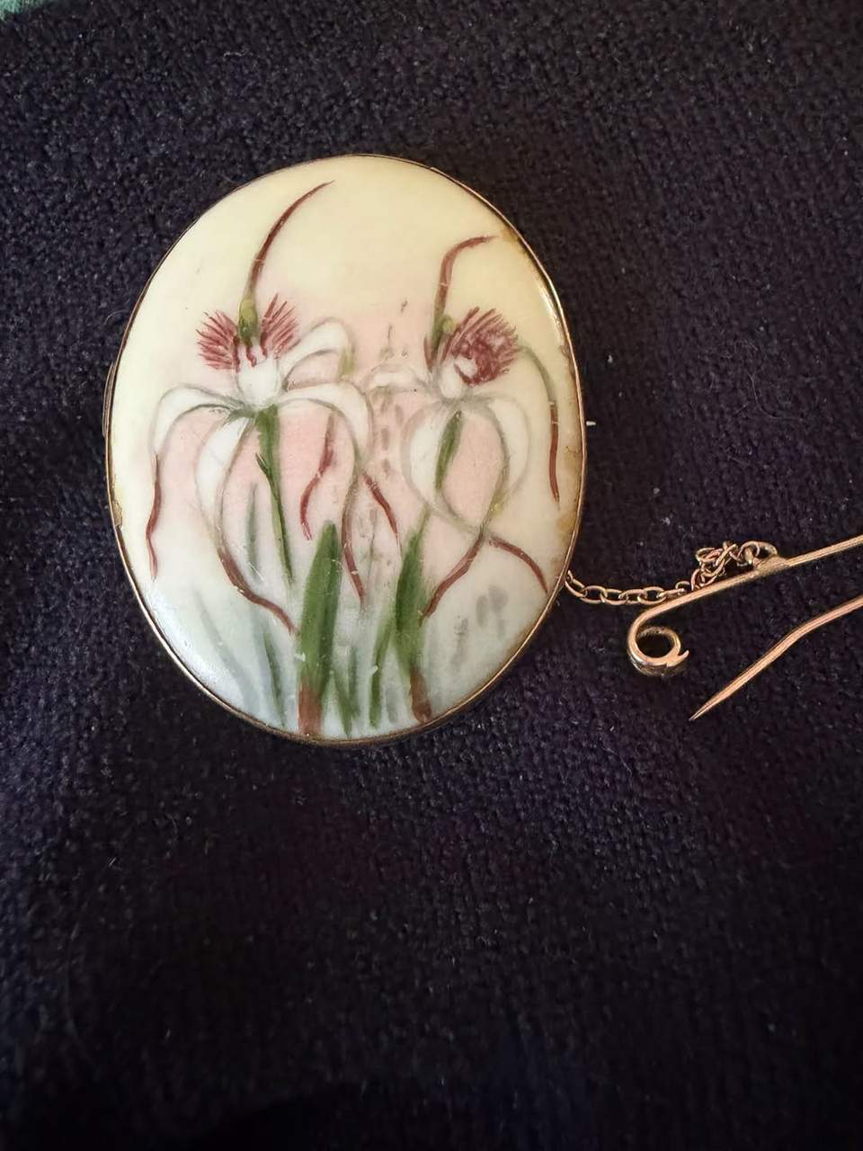 a vintage hand-painted porcelain or ceramic brooch featuring Australian spider orchids, in the style of Western Australian artist May Creeth. Valued $400.  Our price $120